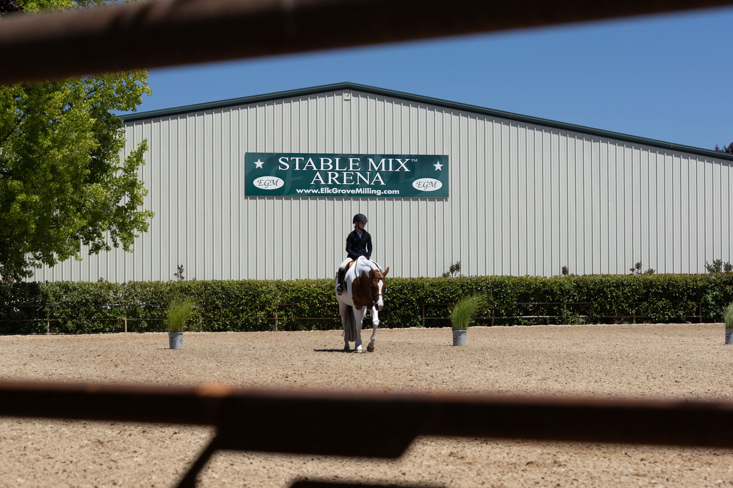 The Stable Mix arena behind a young rider on her paint horse in the JD Pasquetti arena; Photo by Carolynne Smith